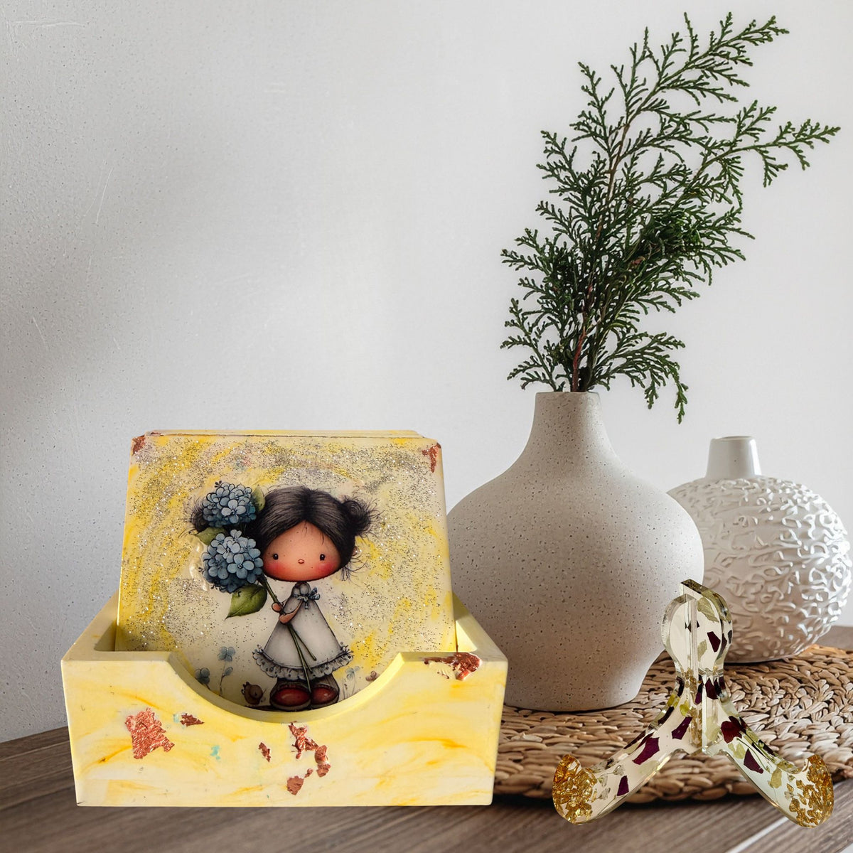 Little Moments handmade coaster set displayed in a yellow marble-effect holder, featuring an illustrated little girl holding blue flowers.
