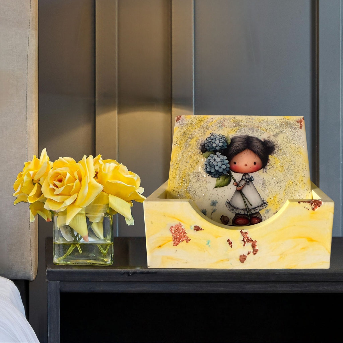 Little Moments handmade coaster set displayed in a yellow marble-effect holder, featuring an illustrated little girl holding blue flowers.