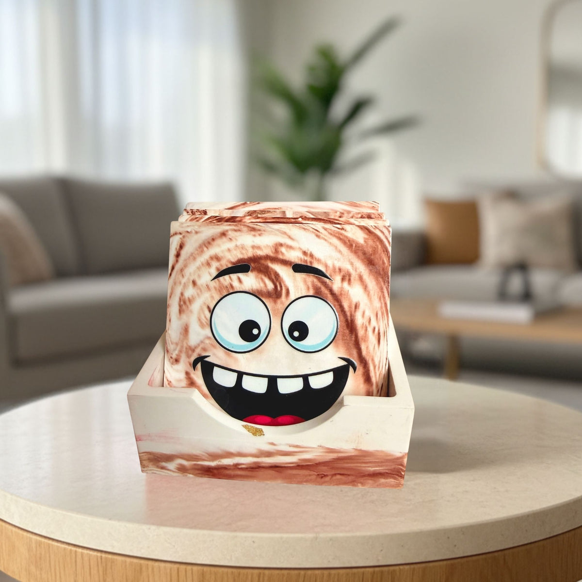 Mood Swings smiling face coaster set displayed in a matching handmade brown and cream marble-effect coaster holder on a coffee table.