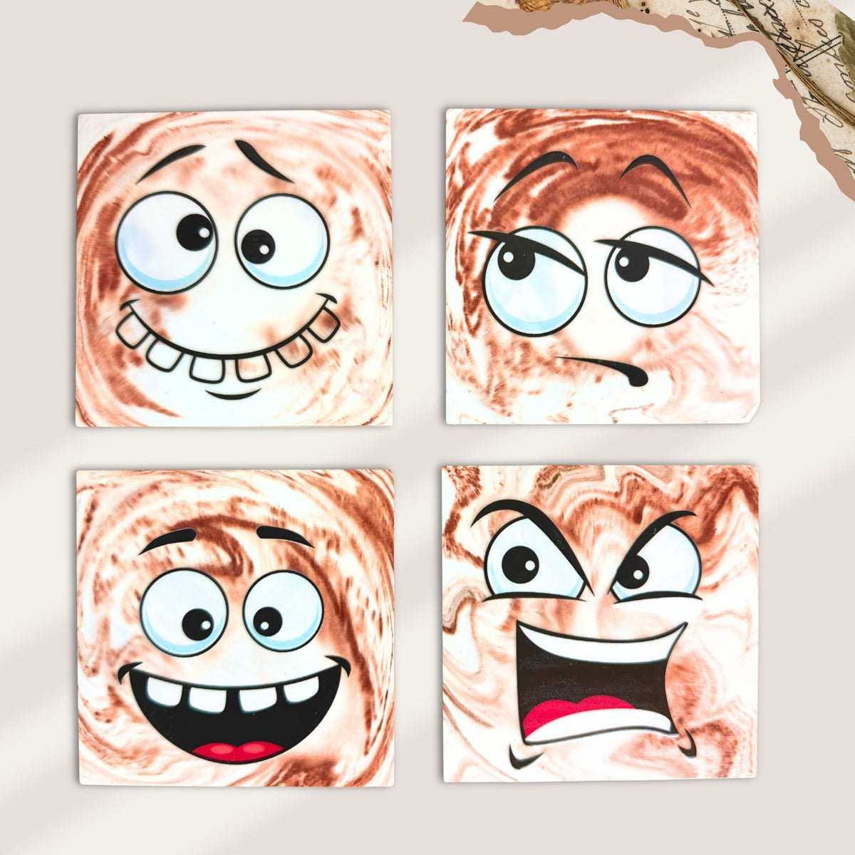 Four brown and cream marble effect coasters each with a fun expression. A playful wide-eyed face with a toothy grin,  an unimpressed side-eye expression, a cheerful cartoon face with wide eyes and an open smile, and a raised eyebrows, wide eyes and an exaggerated open-mouth expression.