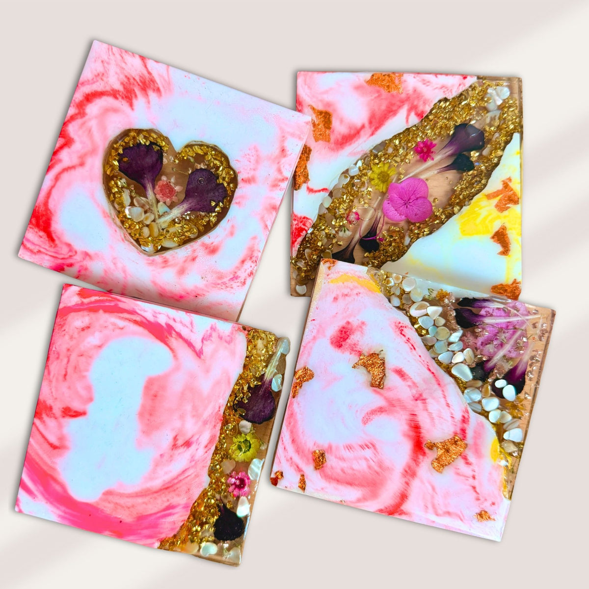 Set of four handmade pink marble-effect coasters with floral details, decorative stones and translucent edges